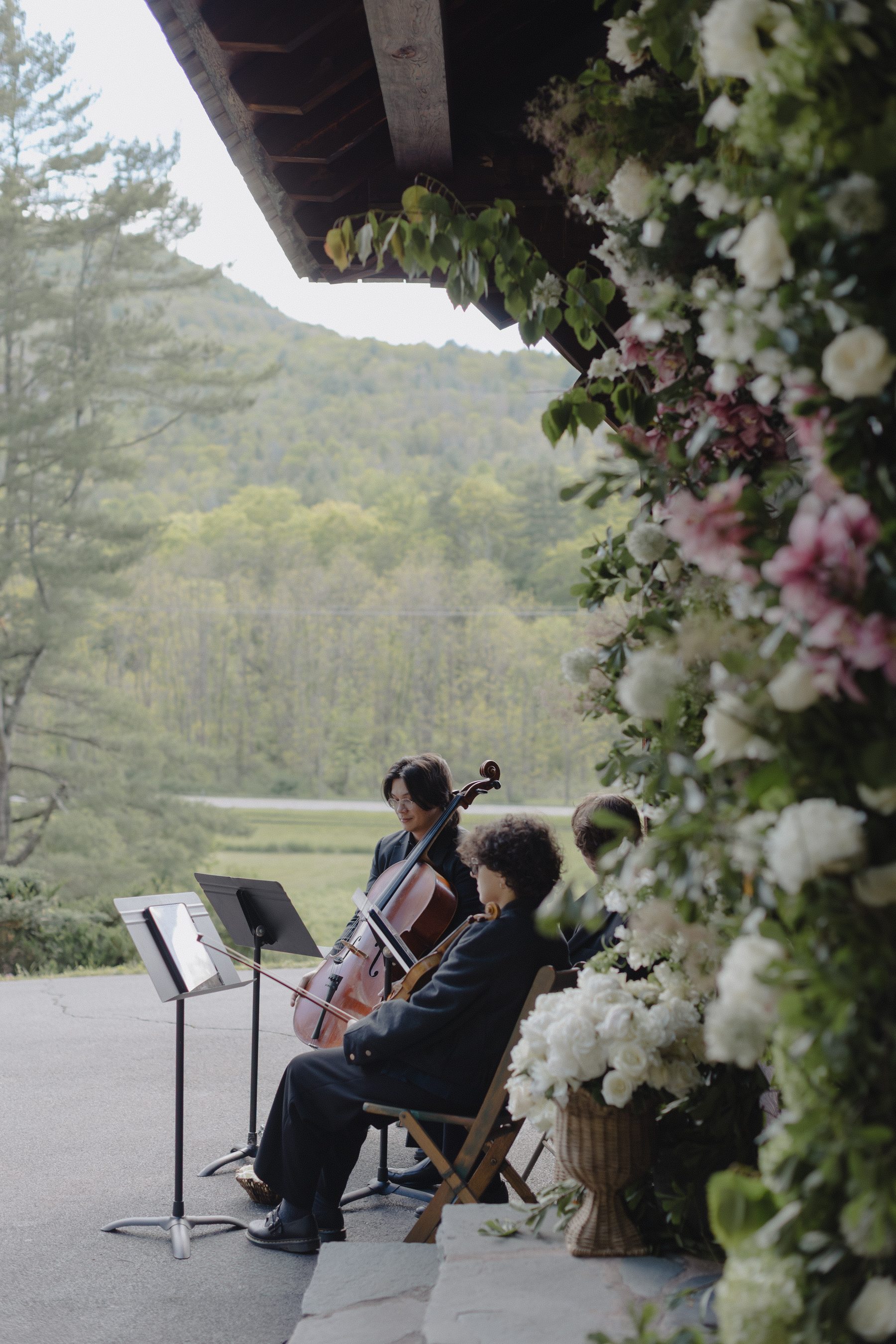 Z-Music string quartet performing an outdoor ceremony beneath a floral arch with mountain views